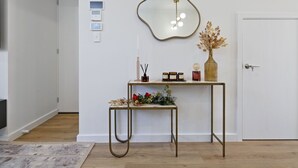 A hallway with a console table, a decorative mirror, and a door. - Quiet Suburban Escape Near Shops & Dining (Blair Athol)
