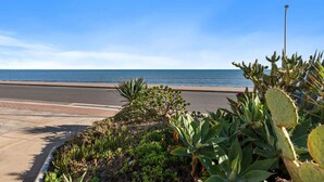 A coastal road with a sidewalk, cactus plants, and a street lamp. - Horizon 235—Seaview Hideaway on the Esplanade (Glenelg North)