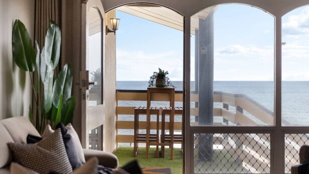 A balcony with a view of the sea, a wooden chair, and a potted plant. - Horizon 235—Seaview Hideaway on the Esplanade (Glenelg North)