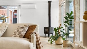 Una sala de estar acogedora con un sofá, una chimenea y plantas en macetas.