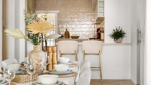 Un comedor con una mesa dispuesta para cuatro personas, con un jarrón con plantas, un cuenco decorativo y un diseño de silla moderno.
