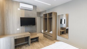 A modern bedroom with a wooden vanity, a flat-screen TV, a walk-in closet, and a large mirror. - Hotel Siel (Durrës)