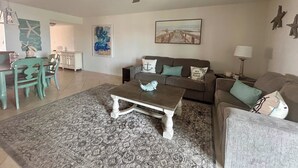 A living room with a ceiling fan, a sofa, a coffee table, and a rug.