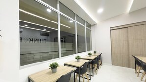 Un espacio de oficina moderno con mesas largas y sillas, ventanas amplias y un interior limpio y blanco.