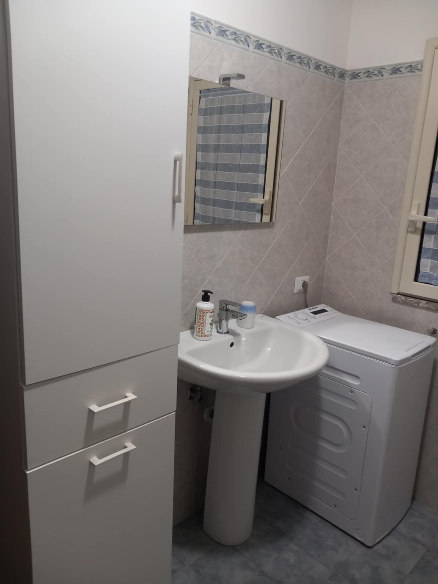 A bathroom with a sink, mirror, and washing machine.