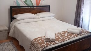 A neatly made bed with a patterned bedspread and rolled towels, a decorative wall mural, a patterned rug, and an air conditioning unit. - Magnolia with private parking (Giardini Naxos)
