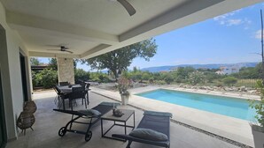 A covered outdoor area with a pool, seating, and a view of the landscape. - Holiday house VILLA AMORA with private pool (Linardići)