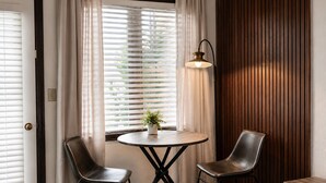 A room with a bed, a round table with two chairs, a potted plant, and a window with blinds. - King Room Near W RMNP + Pool & Hot Tubs (Granby)