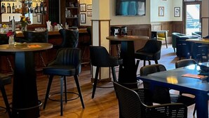 A spacious bar area with wooden floors, black upholstered chairs, and a variety of bar stools. There is a large mirror reflecting the bar area, and a television mounted on the wall. - King Room Near W RMNP + Pool & Hot Tubs (Granby)