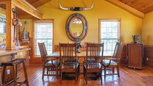 A dining area with a wooden ceiling, a large mirror, and a rustic decor including a horn and a guitar. - Charming Cottage on 70 acre Horse Ranch, 14 miles from I-40, Carroll County, TN (Cedar Grove)