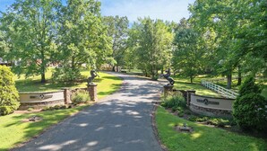 A paved driveway leading to a gated entrance with stone walls and a sign reading "Southern Serenity." - Charming Cottage on 70 acre Horse Ranch, 14 miles from I-40, Carroll County, TN (Cedar Grove)