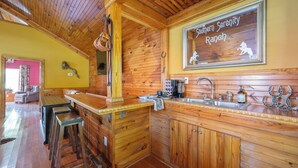 A rustic wooden interior with a bar area, a sink, and a framed sign reading "Southern Serenity Ranch". - Charming Cottage on 70 acre Horse Ranch, 14 miles from I-40, Carroll County, TN (Cedar Grove)