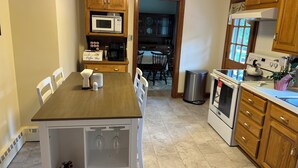 A kitchen with wooden cabinets, a microwave, a coffee maker, and a stove.