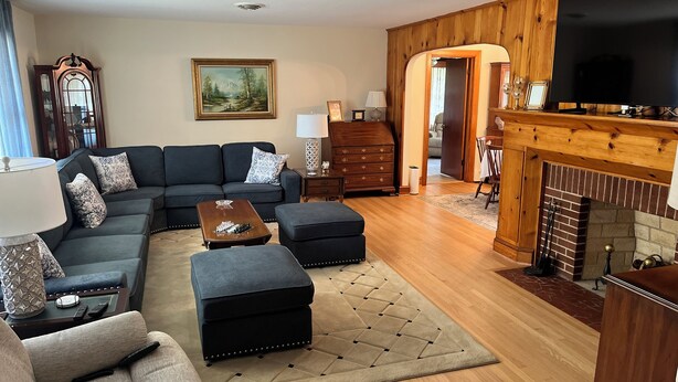 A living room with a sectional sofa, ottoman, coffee table, fireplace, and a television.