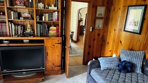 A cozy room with a wooden bookshelf, a television, and a comfortable sofa.