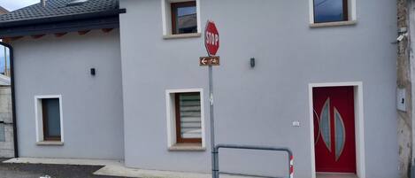 A building with a stop sign, a bicycle symbol, and a red door.