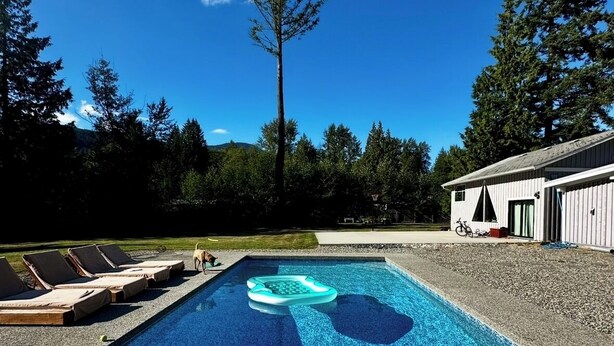 A swimming pool with lounge chairs, a floating ring, and a building in the background.
