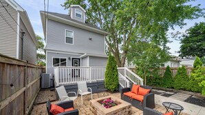 A backyard patio with outdoor furniture, a fire pit, and a wooden fence. - The Southern Nook - For 8 (Columbus)