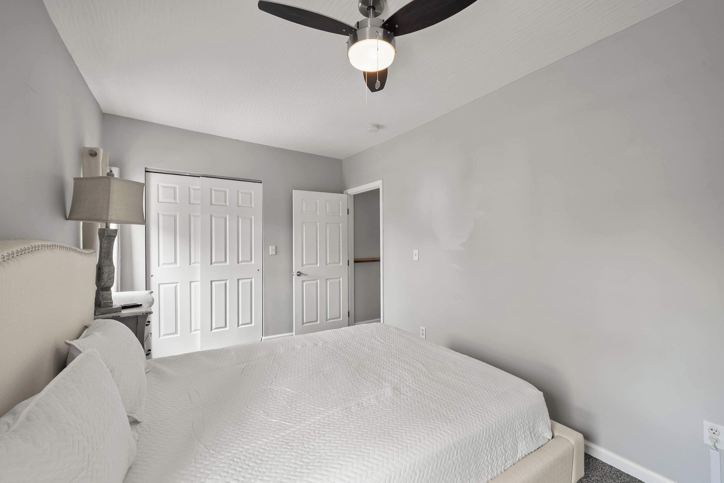 Une chambre à coucher avec un lit, un ventilateur de plafond et deux portes.