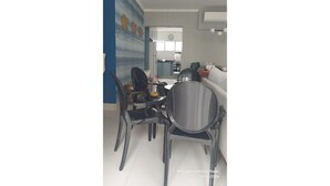 Un coin repas avec une table et des chaises, une cuisine en arrière-plan et un mur d’accent bleu.