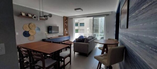 A modern living room with a dining area, a sofa, and a TV.