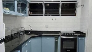 Une cuisine avec des meubles de couleur bleue, un plan de travail noir, une cuisinière et un four à micro-ondes.