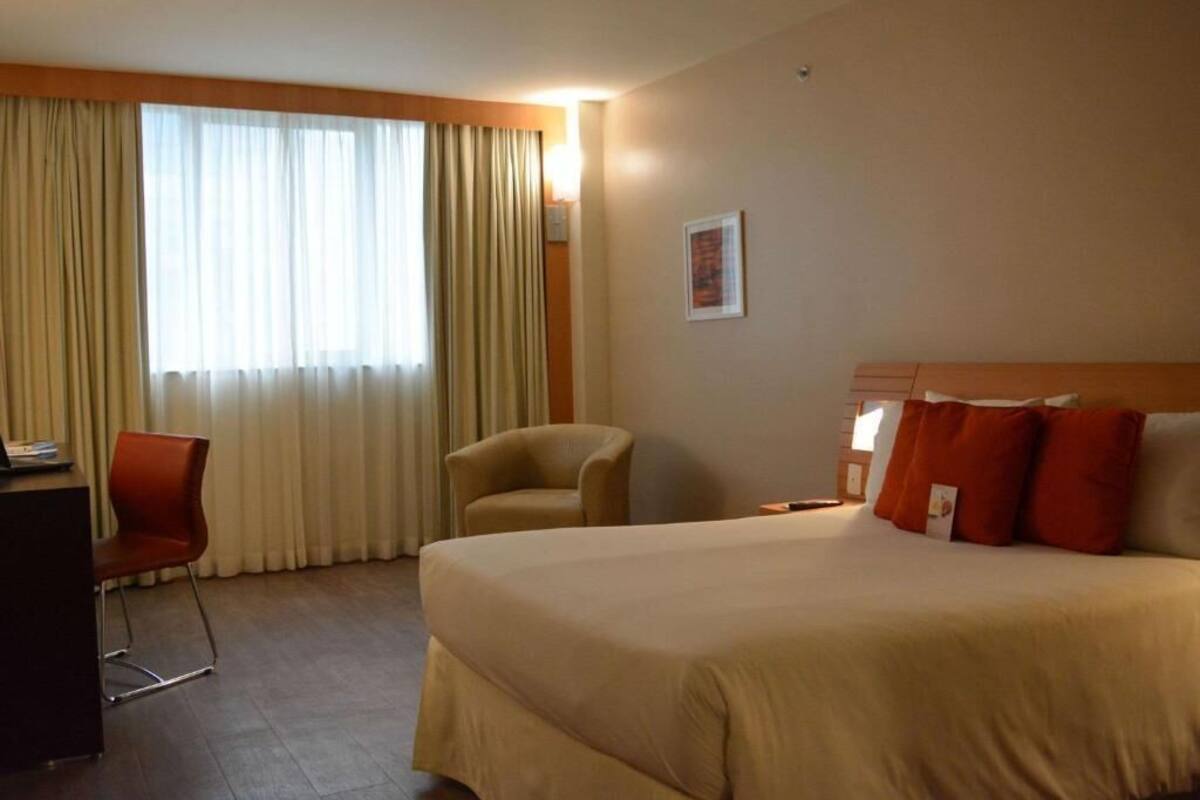 Una camera d'albergo con un letto grande, una scrivania, una sedia e una finestra con tende.