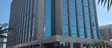 Un moderno edificio de hotel con fachada de vidrio y un letrero que dice 'Regency Barra Hotel'.
