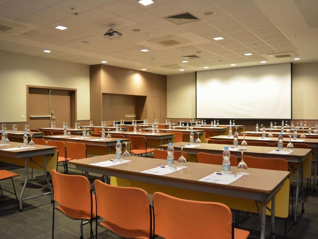 A conference room with rows of tables, chairs, and water bottles.