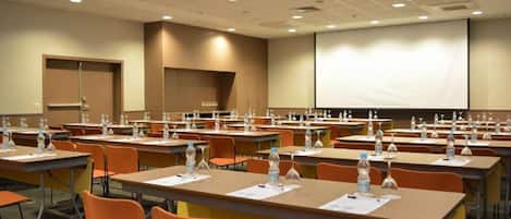A conference room with rows of tables, chairs, and water bottles.