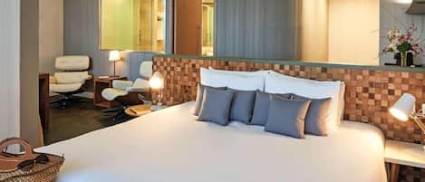 Una habitación de hotel con una cama grande, un escritorio, una silla y un espejo.