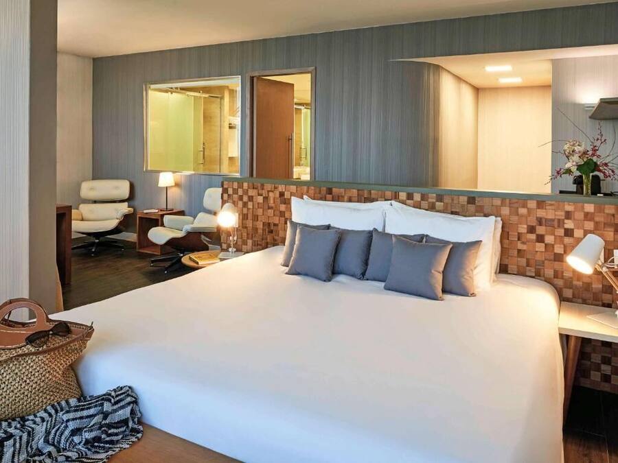 Una habitación de hotel con una cama grande, un escritorio, una silla y un espejo.