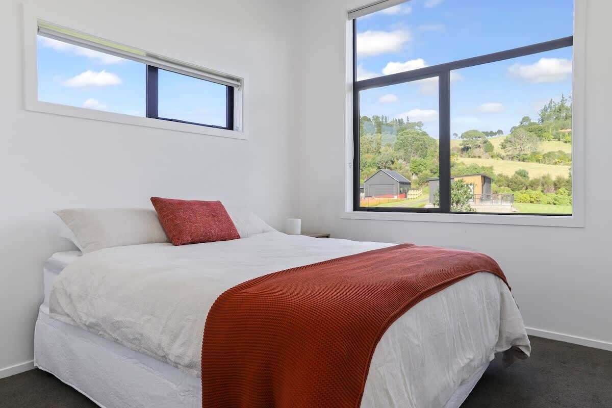 A bedroom with a bed, a window, and a view of a landscape.