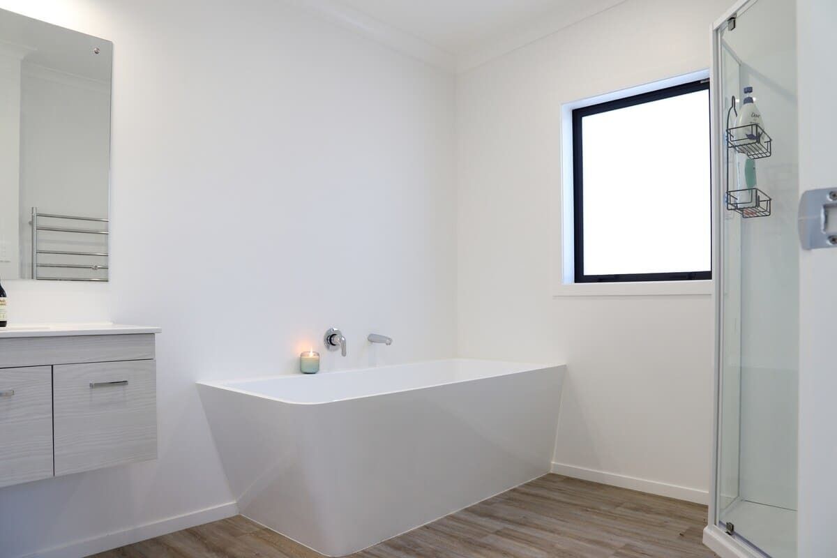Une salle de bain moderne avec une baignoire sur pieds, une douche à parois de verre et une fenêtre laissant entrer la lumière naturelle.