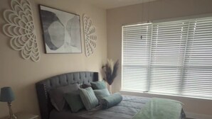 A bedroom with a bed, a nightstand, a ceiling fan, and a window with blinds. - HTX Luxury Downtown Apartments 10 mins away from galleria mall private parking (Houston)