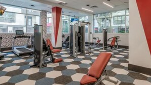 A gym with cardio machines, weight stations, and red exercise chairs. - HTX Luxury Downtown Apartments 10 mins away from galleria mall private parking (Houston)