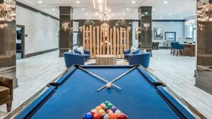 A pool table in a modern hotel lobby with a wooden partition and blue seating. - HTX Luxury Downtown Apartments 10 mins away from galleria mall private parking (Houston)