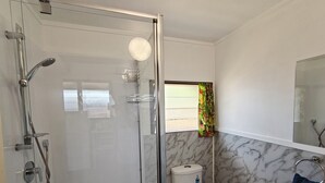 A bathroom with a glass-enclosed shower, a toilet, and a sink. - Sunset Bugalows (Aitutaki)