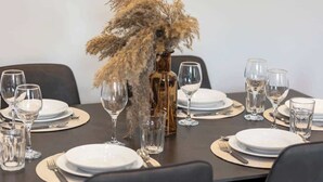 Una mesa de comedor dispuesta con platos, vasos y cubiertos, con un jarrón decorativo en el centro.