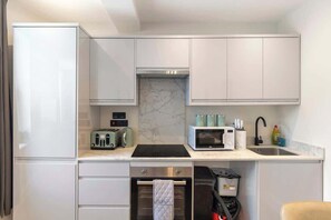 Una cocina compacta con horno integrado, microondas, tostadora y lavabo.