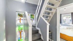 A staircase with a white handrail, grey carpeted steps, and a door leading to a bedroom with a bed. - Spacious House with Private Entrance (London)