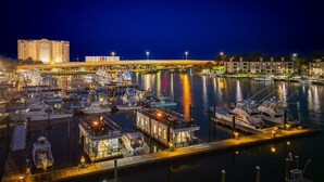 Eine Marina bei Nacht mit vertäuten Booten, eine Brücke im Hintergrund und Gebäude am anderen Ufer.