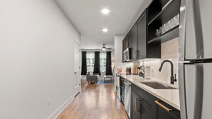 Una cocina moderna con armarios oscuros, electrodomésticos de acero inoxidable y piso de madera.