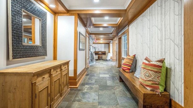 A hallway with a wooden bench, a mirror, and a patterned wall. - ⛷️Slope side Condo- (Stratton)