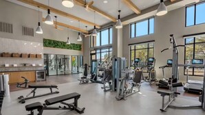 A modern gym with various exercise equipment, large windows, and a clean, open floor plan. - The Perfect Studio | 1 Queen Bed | Raymond James! (Tampa)