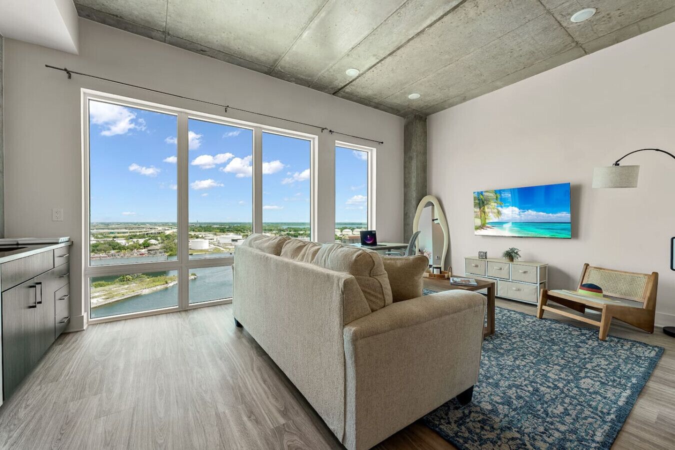 Una sala de estar moderna con un ventanal grande, un sofá, una mesa de centro y vistas a un paisaje costero.