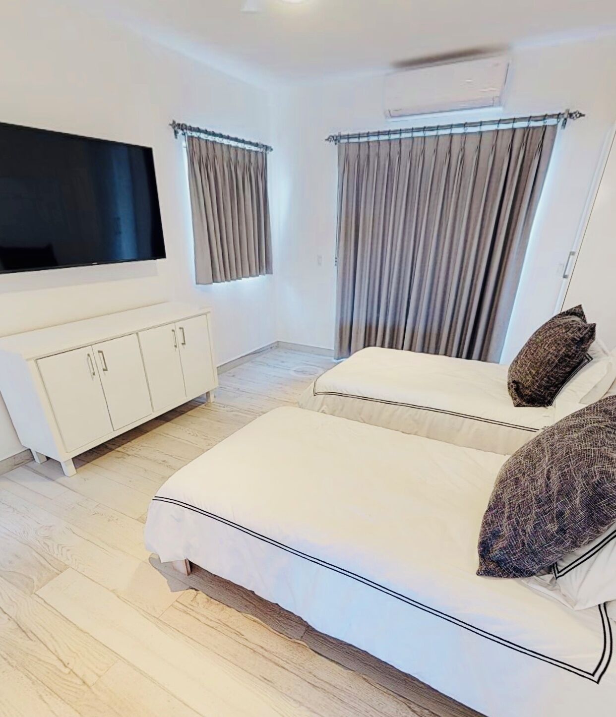 Une chambre à coucher avec un lit, une télévision, une armoire et des rideaux.