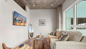 Una sala de estar moderna con un sofá, una mesa de centro, un espejo y obras de arte en las paredes.