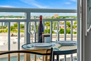 A balcony table with two wine glasses, a bottle of wine, and a candle labeled "SAND + FOG". - Stunning Studio | New and Luxury | Free Parking! (Tampa)