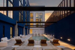 A rooftop pool area with lounge chairs and tables, surrounded by blue walls and a modern building. - Central Ybor Studio | Free Parking | Mins to DT! (Tampa)